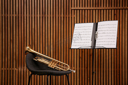 小号、椅子和笔记站立与音乐板料在木墙壁背景