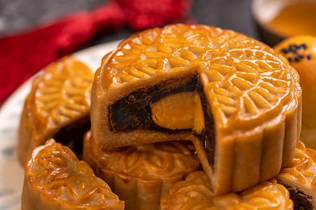 为中秋节烤的美味蛋黄糕点月饼，背景为黑色石板黑色。中国节庆食品的概念，闭合，复制空间.