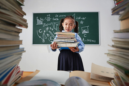 搬书摄影照片_搬着沉重课本的小学女生