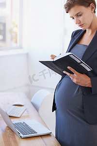 确认她的产假一个怀孕的女商人在她的办公室里看她的日常计划.