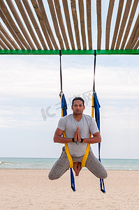 海面背景摄影照片_反重力瑜伽，做瑜伽练习的海面背景的人