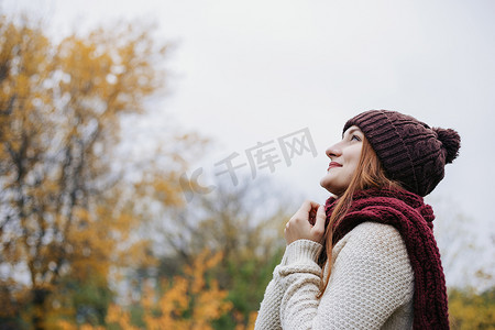 模特穿着暖和的冬帽, 毛衣和红围巾, 仰望天空。那女孩把双臂搂在胸前。女人牵着她的手在围巾上。户外。个人资料肖像.