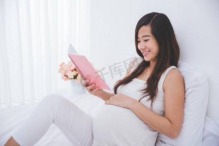 美丽亚洲孕妇阅读笔记书，微笑