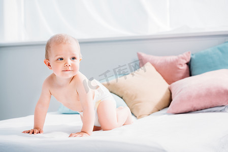 古人枕头摄影照片_快乐的小宝宝爬在床上, 许多枕头和看着远离