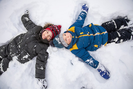 快乐的男孩在雪地里玩耍，在户外阳光灿烂的一天微笑