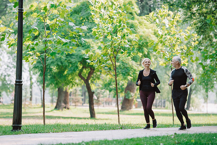 一起看看表情包摄影照片_运动成熟的运动员和女运动员一起在公园里慢跑