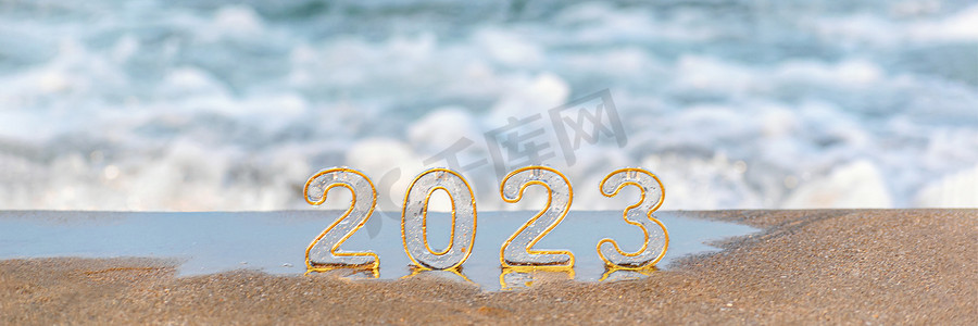 Happy new year 2023 wide banner, background. Numbers 2023 on golden sand of beach and blurry sea wave. New Year's Eve holidays celebration, travel, vision, dreams, goals concept, copy space