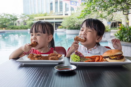 亚洲小中国女孩吃的汉堡和炸鸡