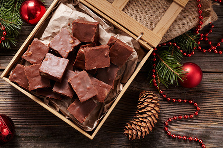 Christmas fudge traditional homemade chocolate sweet dessert food in wooden box on vintage table background. Top view. Delicious unhealthy snack.