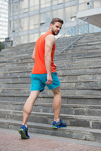 男子在积极的磨损和运动鞋的步骤。运动员在楼梯上锻炼。适合和自信。未来和成功。准备克服任何障碍。体育和训练活动