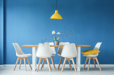 吊灯餐厅摄影照片_蓝色餐厅室内配有大桌子、白色椅子和黄色吊灯