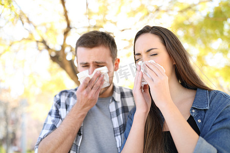 一对生病的夫妇在公园里打喷嚏，用湿巾捂住嘴