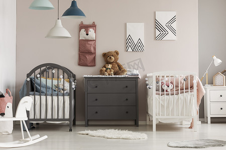 棕色泰迪熊在灰色木制房管之间两个婴儿床在时尚卧室为双胞胎