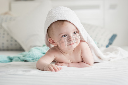 快乐的 9 个月大婴儿浴后在毛巾下看