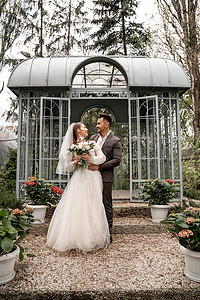 full摄影照片_full length view of happy couple of newlyweds looking at each other near alcove in park