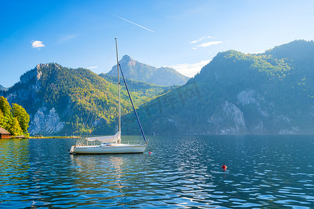 在瑞士高山背景下的一艘游艇。平静的水和灿烂的晴天。一个受欢迎的旅行和放松的地方. 
