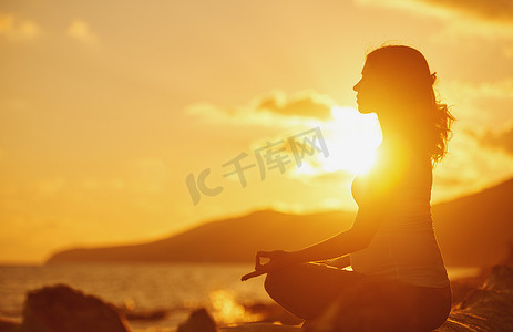 瑜伽毛笔字体摄影照片_孕妇练瑜伽在荷花在阳光沙滩上的立场