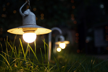 园林设计摄影照片_小花园灯, 草床上的灯笼。园林设计。灯光和圣诞灯饰在晚上装饰着一个花园。婚礼上的灯光和灯笼。博凯.