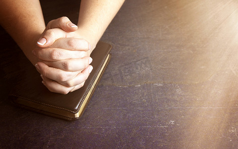 一个女人双手紧握着圣经祈祷