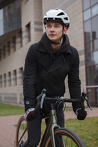 头戴安全帽摄影照片_一个骑自行车、头戴安全帽的男子在城市中的垂直镜头
