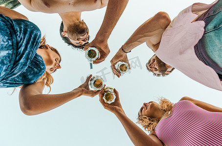 底部通知栏摄影照片_一群快乐的朋友在海滩边户外品酒和烘焙啤酒- -与年轻人在夏季酒吧一起玩乐的友谊理念- -从底部看天空背景