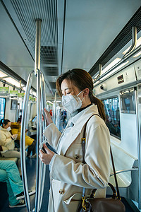 地铁戴口罩摄影照片_戴口罩的年轻女人乘坐地铁