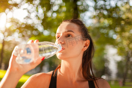夏季公园锻炼后, 年轻的运动妇女喝水。健康的生活方式。积极的生活方式