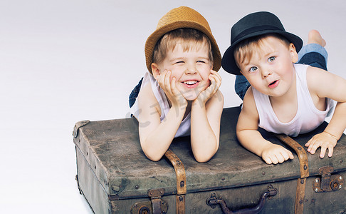 Two cute brothers lying on luggages