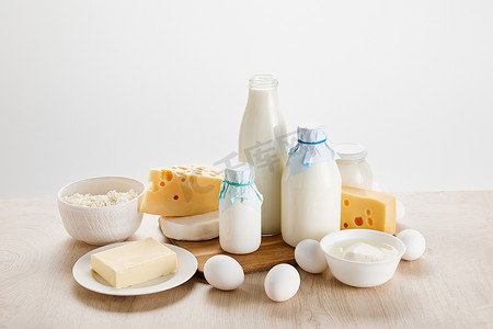 奶制品摄影照片_木制桌子上的各种新鲜有机奶制品和鸡蛋，与白色隔离