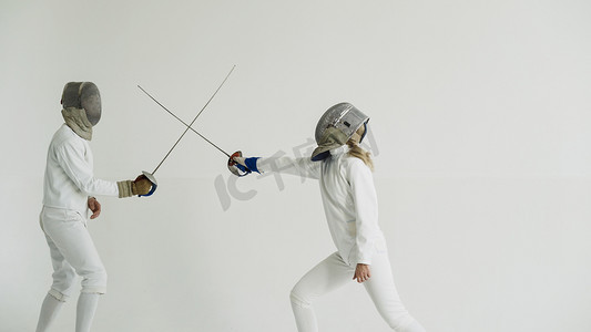 年轻女子击剑手击剑教练在白色演播室室内训练