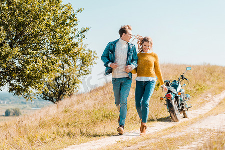 快乐的夫妇运行在农村草地上的摩托车背景