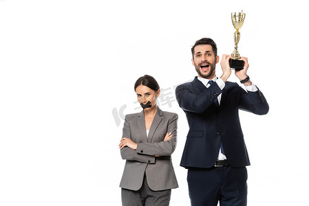 兴奋的商人拿着奖杯站在女商人身边，嘴上缠着胶带，双臂交叉，与白人隔离