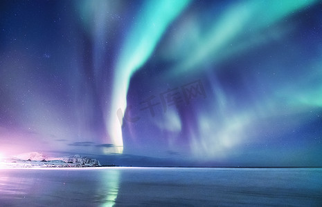 足底反射区摄影照片_挪威洛福敦群岛上的北极光。夜晚的天空与极光。夜间冬季景观与极光和反射的水面上。挪威的自然背景