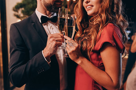 一对年轻貌美的情侣穿着正装，一边用香槟酒敬酒，一边在豪华派对上共度时光