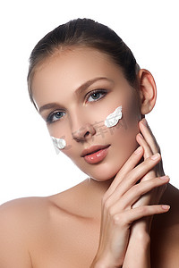 Skin care lady putting face cream. Attractive brunette girl on white background. Beautiful face of young woman with cosmetic cream on a cheek. Skin care concept. Skincare products