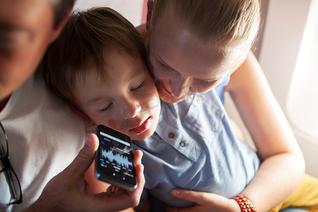 music摄影照片_Child sleeping with music on cell phone in plane