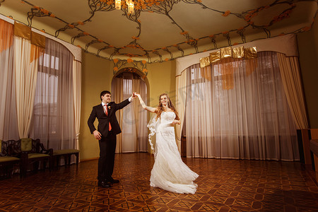 在令人惊叹的老式宽敞的大厅与木拼花地板和模式天花板的美丽婚礼夫妇的婚礼舞蹈.