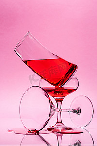 形状组合摄影照片_三种不同形状的玻璃与浅粉色背景上的红色液体的组合.