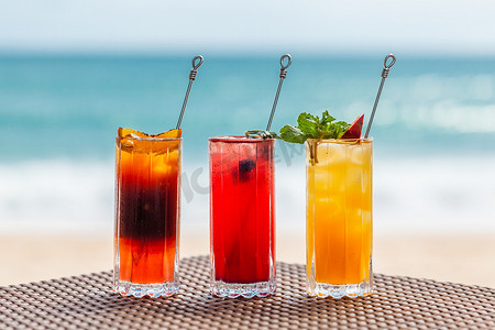 位于绿松石海附近海滩上的一组清爽的水果鸡尾酒