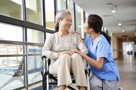 friendly asian caregiver talking to senior resident in nursing h