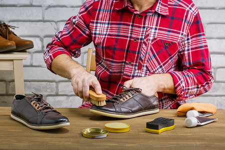 人在工作场所的木制桌子上用刷子擦亮皮鞋.小商业.