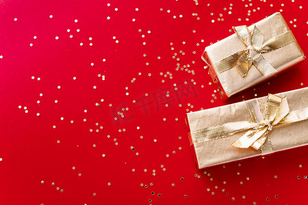 迎接背景摄影照片_红色的圣诞或新年的背景，纯正的金色圣诞礼物和金色的星星。平淡的，空的空间迎接文本。圣诞节的概念