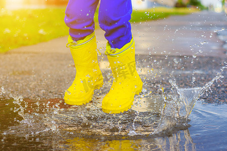 我的橡胶脚踏在水坑里。关于橡胶靴的文章。孩子们的夏鞋雨后抱抱.坏天气。一个孩子跳进了水坑里.一个穿着橡胶靴的快乐男孩跳进了水坑.