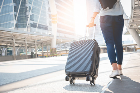 女旅客旅客在候机楼提着行李散步。活动和生活方式概念。商务人士与长假主题。后视图
