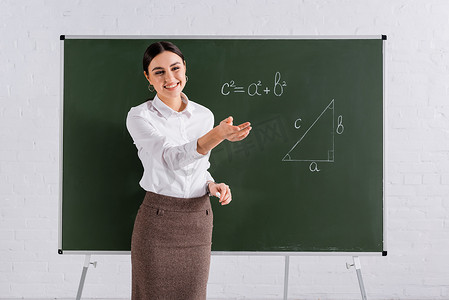 数学课期间，教师用手靠近黑板微笑 