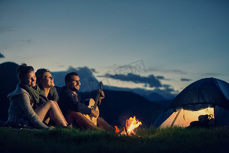火与火摄影照片_三个朋友在日落时分与火山上露营