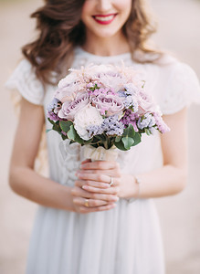 结婚花束的白色和紫色的颜色，关闭。适度美丽的笑容满面的新娘与圆紫色婚纱。白色花边和丝绸婚纱。幸福的婚礼概念