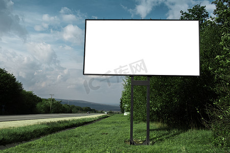 蓝天背景下，在柏油路和绿林附近贴广告海报的空广告牌.