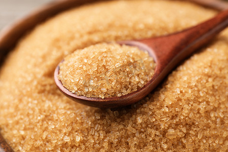 Wooden bowl and spoon with brown sugar, closeup