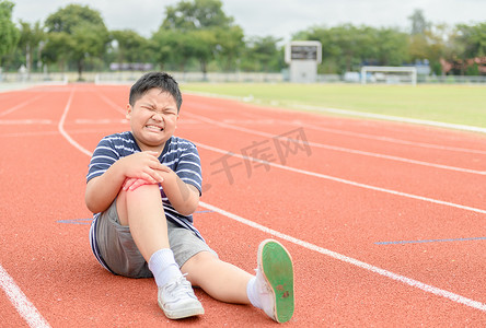 膝盖胀痛摄影照片_肥胖男孩感到疼痛后, 他的膝盖受伤的轨道上, 运动运动损伤概念